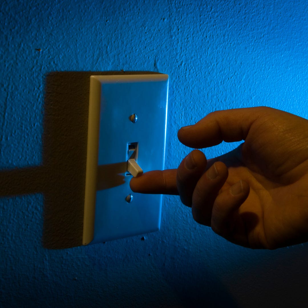 hand reaching for a light switch in a darkened room