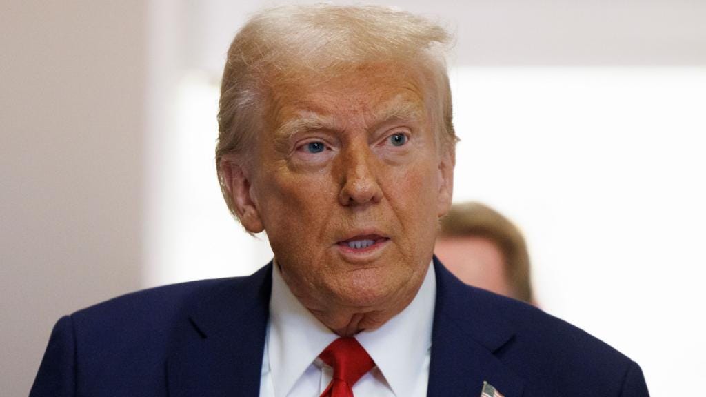 Donald Trump, wearing a blue suit and red tie, looks off to the left with his mouth open