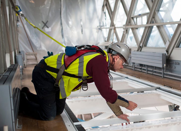 A man in high vis fitting the glass walkway on Tower Bridge