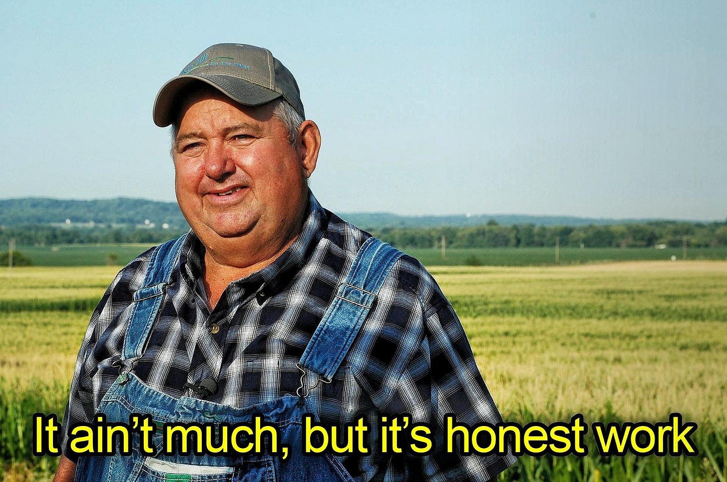 The meme of a farmer standing in front of a field stating "It ain't much, but it's honest work"
