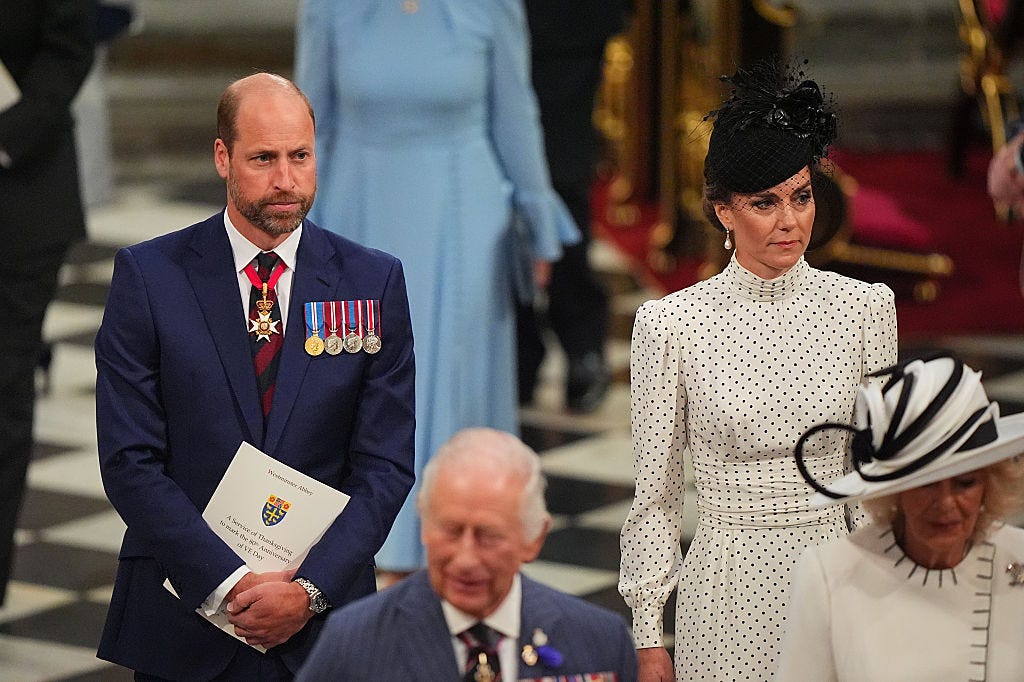 Prince William wearing a blue suit with medals and Princess Kate in a polka dot dress