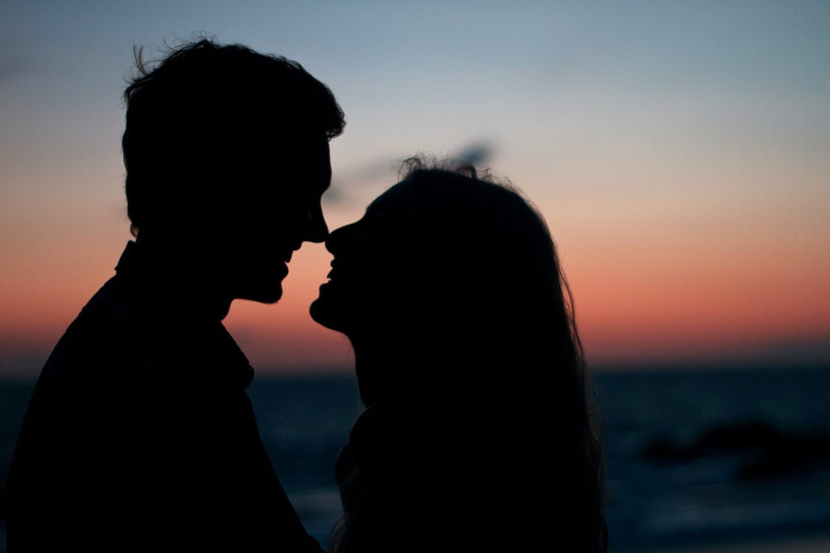 Lovers silhouetted against sunset at dusk