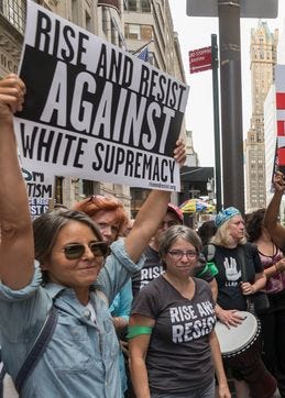 Photo of white woman holding sign against white supremacy.