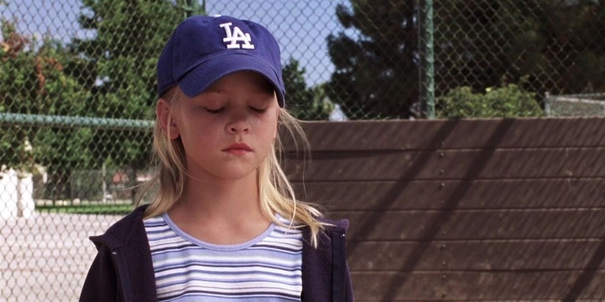 Still from A Cinderella Story, showing Young Sam with her Dodgers hat on at the baseball field, looking sad because her dad just died.