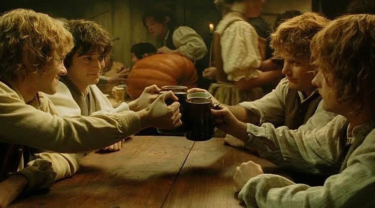 The hobbits from the Lord of the Rings toasting each other at the Prancing Pony.