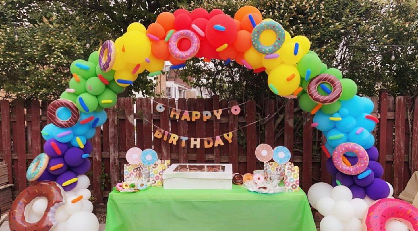 A rainbow balloon arrangement with donut balloons attached to it.