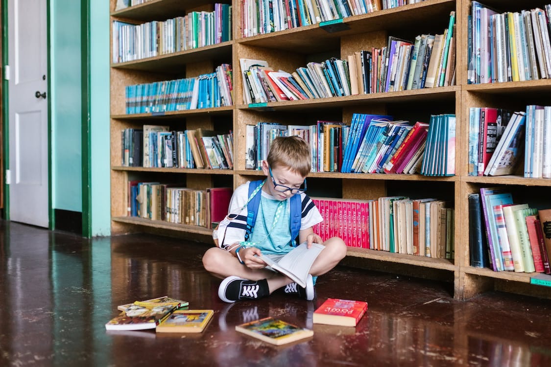 Free Boy Sitting on Floor Reading a Book Stock Photo