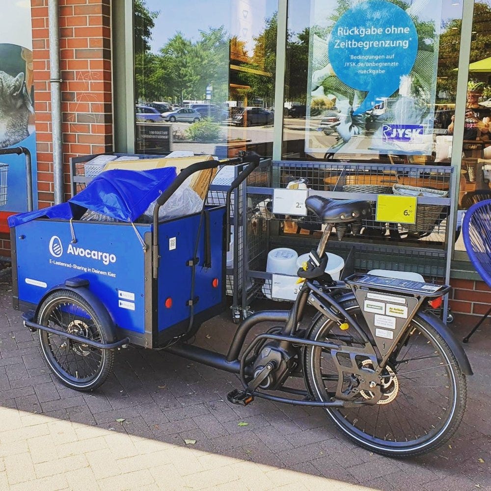 A blue and brown cargo bike is parked in front of a shop window in Berlin.