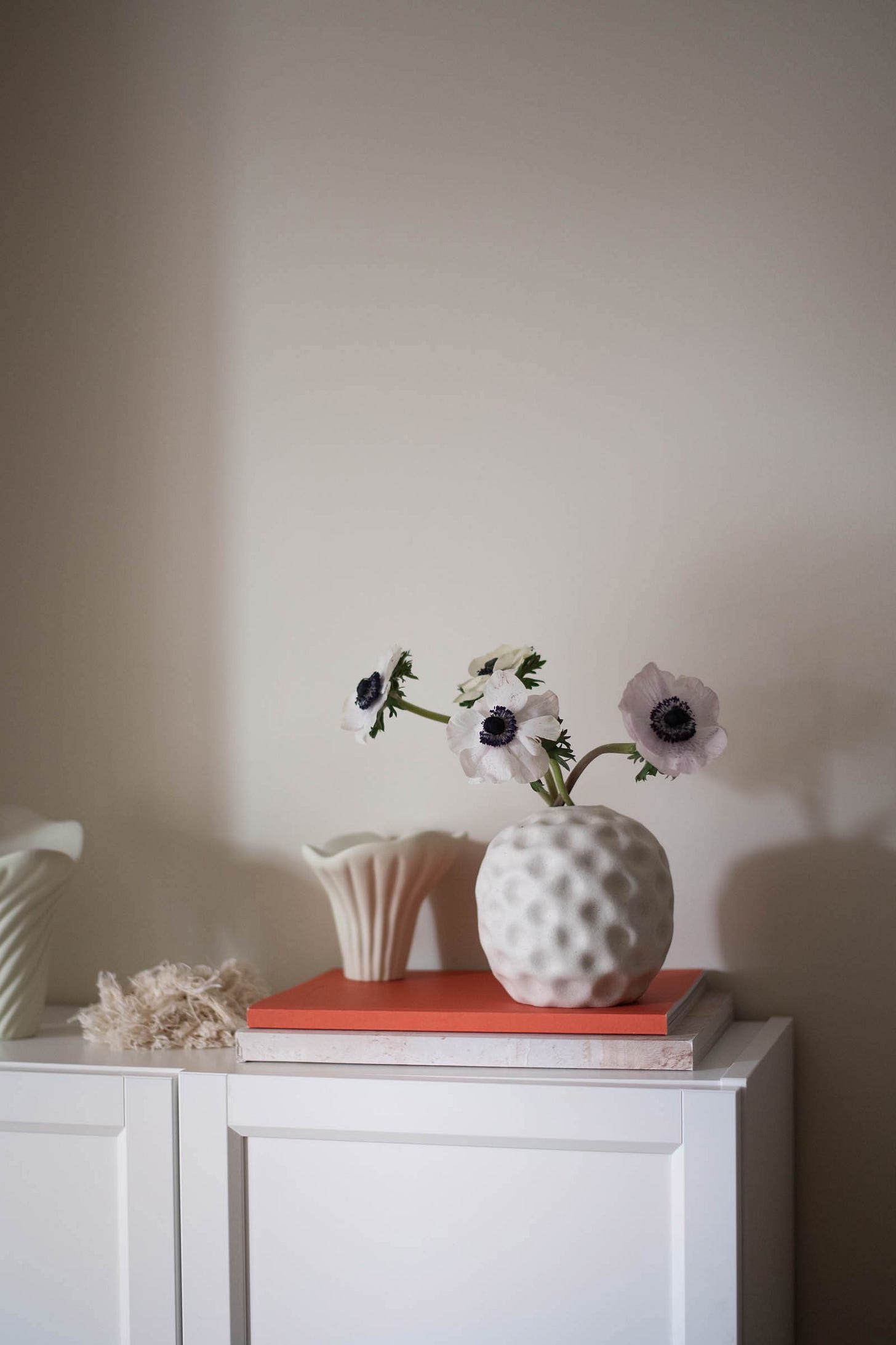 anemones in a white vase on a credenza
