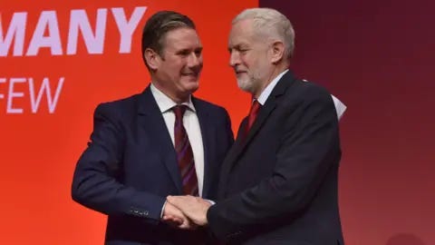 A smiling Sir Keir Starmer shakes hands with then Labour leader Jeremy Corbyn at a party conference in 2017