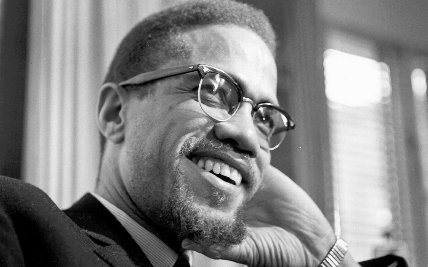 a black and white image of malcolm x smiling