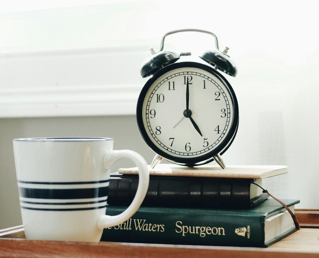 white ceramic mug beside white and black analog alarm clock white ceramic mug beside white and black analog alarm clock