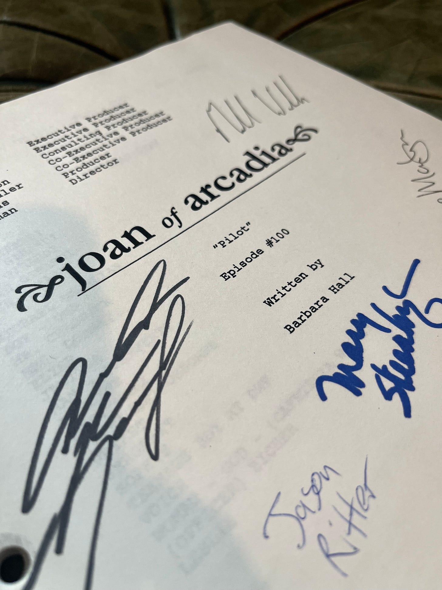 The title page of the "Joan of Arcadia" pilot script. Text reads: "Pilot - Episode #100 Written by Barbara Hall." Signatures of various cast members cover the page.
