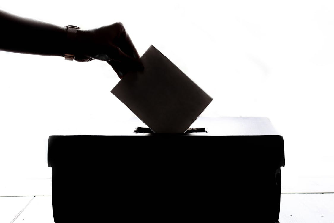 Free Silhouette of a hand placing a vote into a ballot box, symbolizing democracy. Stock Photo Free Silhouette of a hand placing a vote into a ballot box, symbolizing democracy. Stock Photo