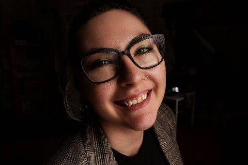 A woman smiles into a camera