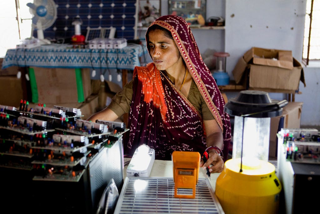 Indian woman sits in a workshop in front of electronics working on solar panel engineering