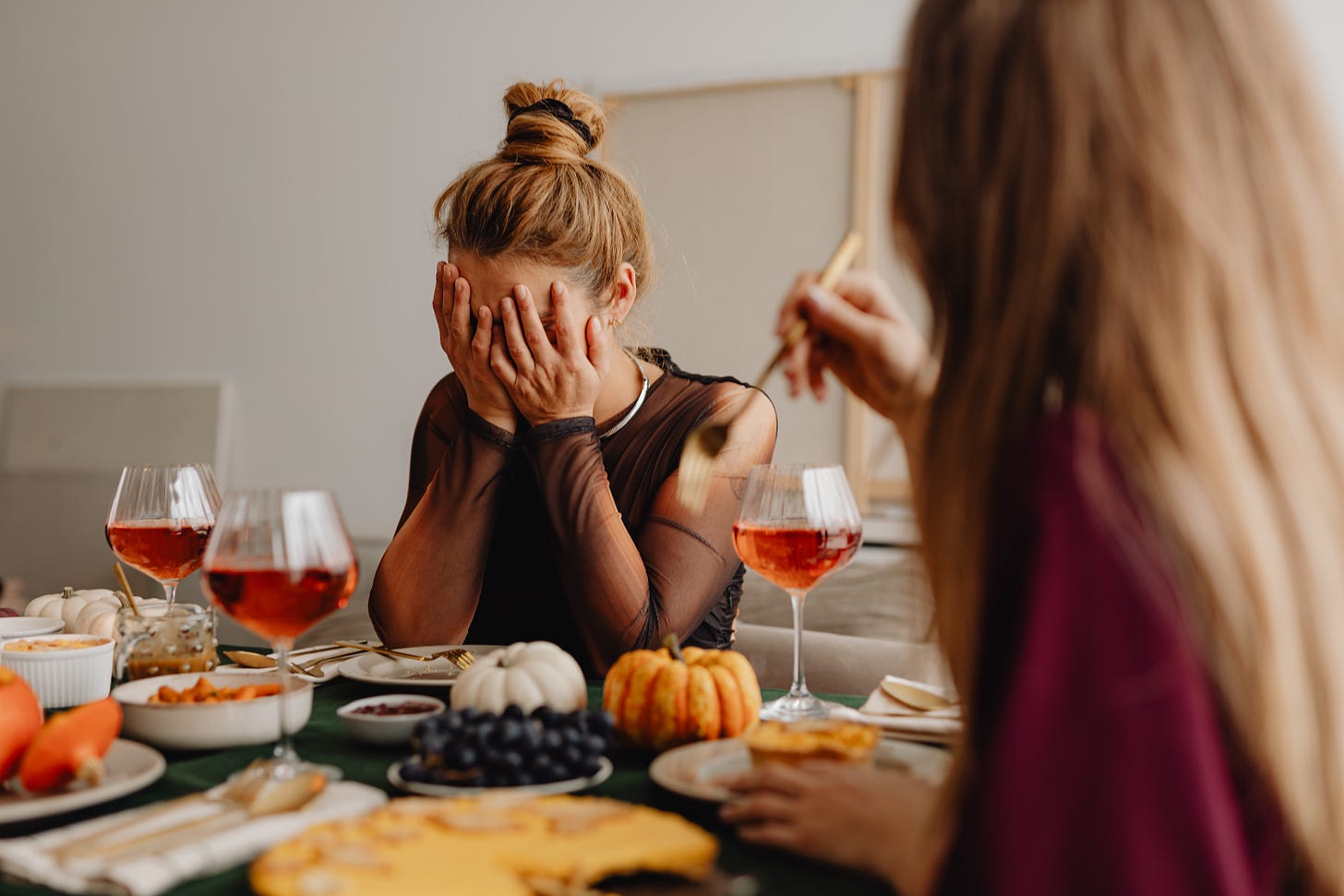 Woman has face in her hands at Thanksgiving dinner