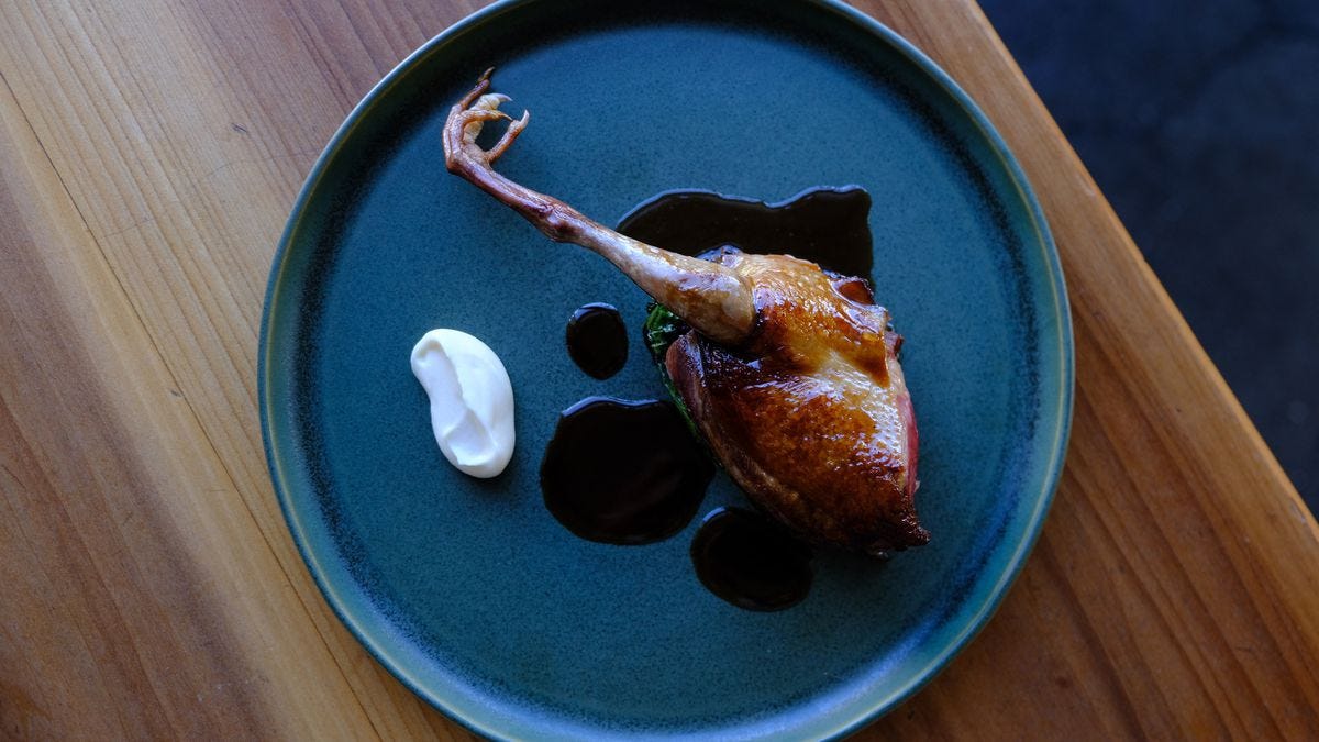A squab leg on a plate with sauce.