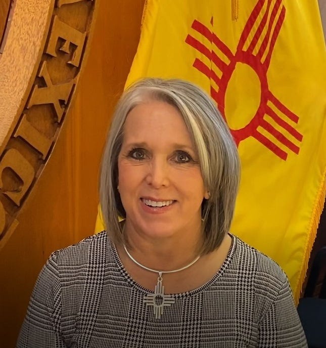 Video screenshot of New Mexico Gov. Michelle Lujan Grisham standing in front of the state flag and seal