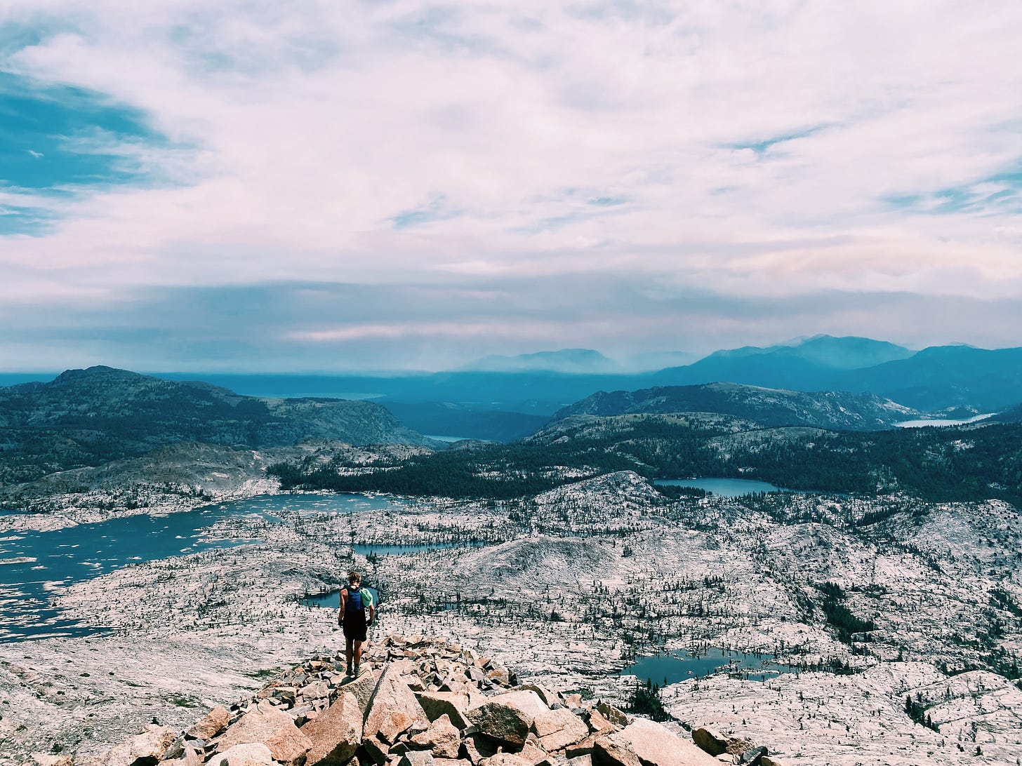 View from behind of me on top of a peak, overlooking a granite lake basin