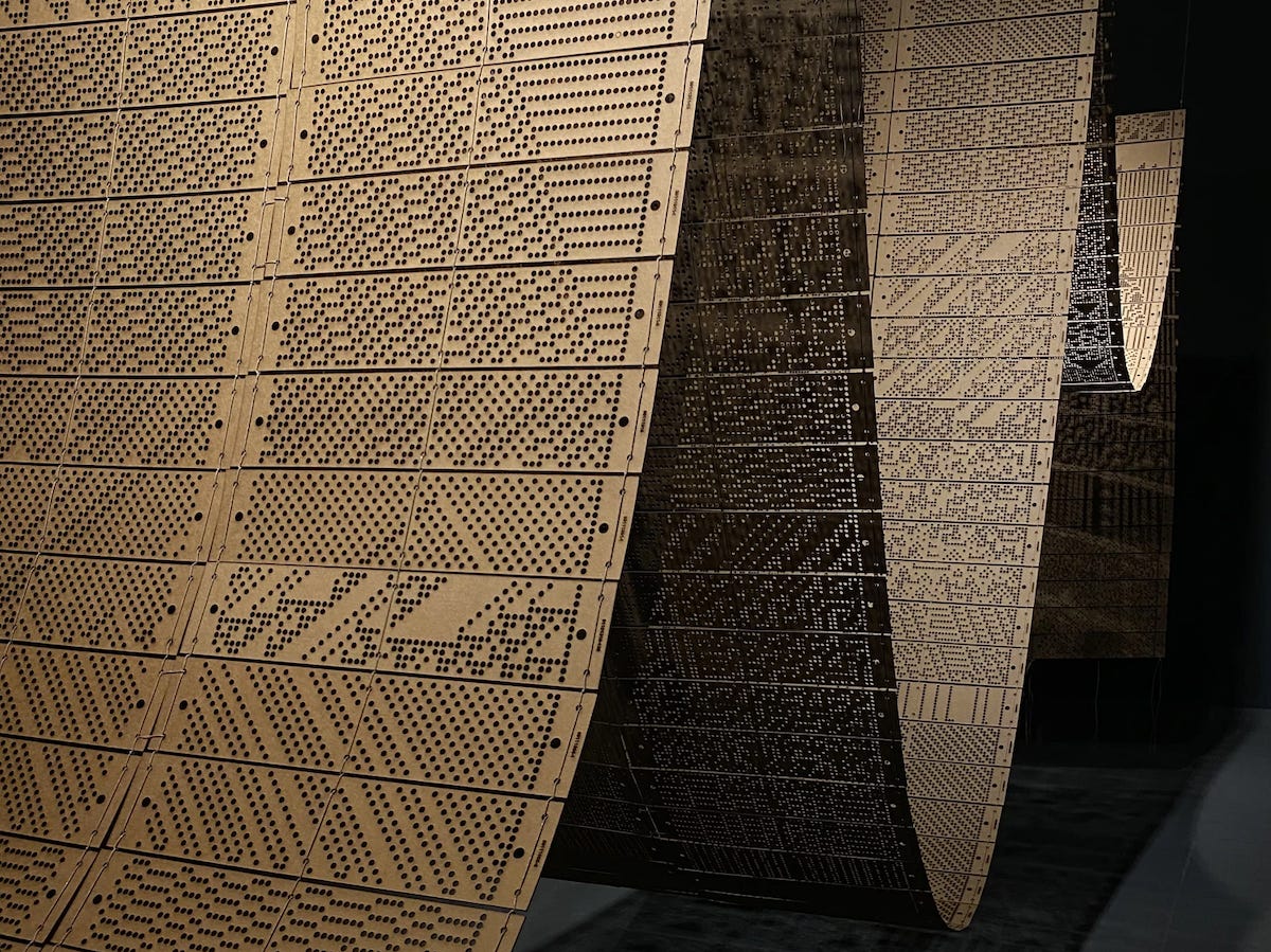 Punch cards suspended and stitched together to resemble waves.