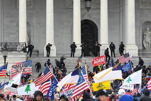 Rioters outside the Capitol on Jan. 6, 2021, waving several flags including American flags, MAGA and Trump flags, and the “Appeal to Heaven” flag.