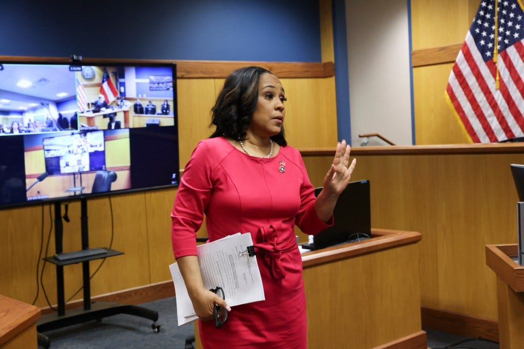 Fani Willis, in red dress, steps away from the stand after testifying during a hearing on Georgia election interference case in Atlanta.