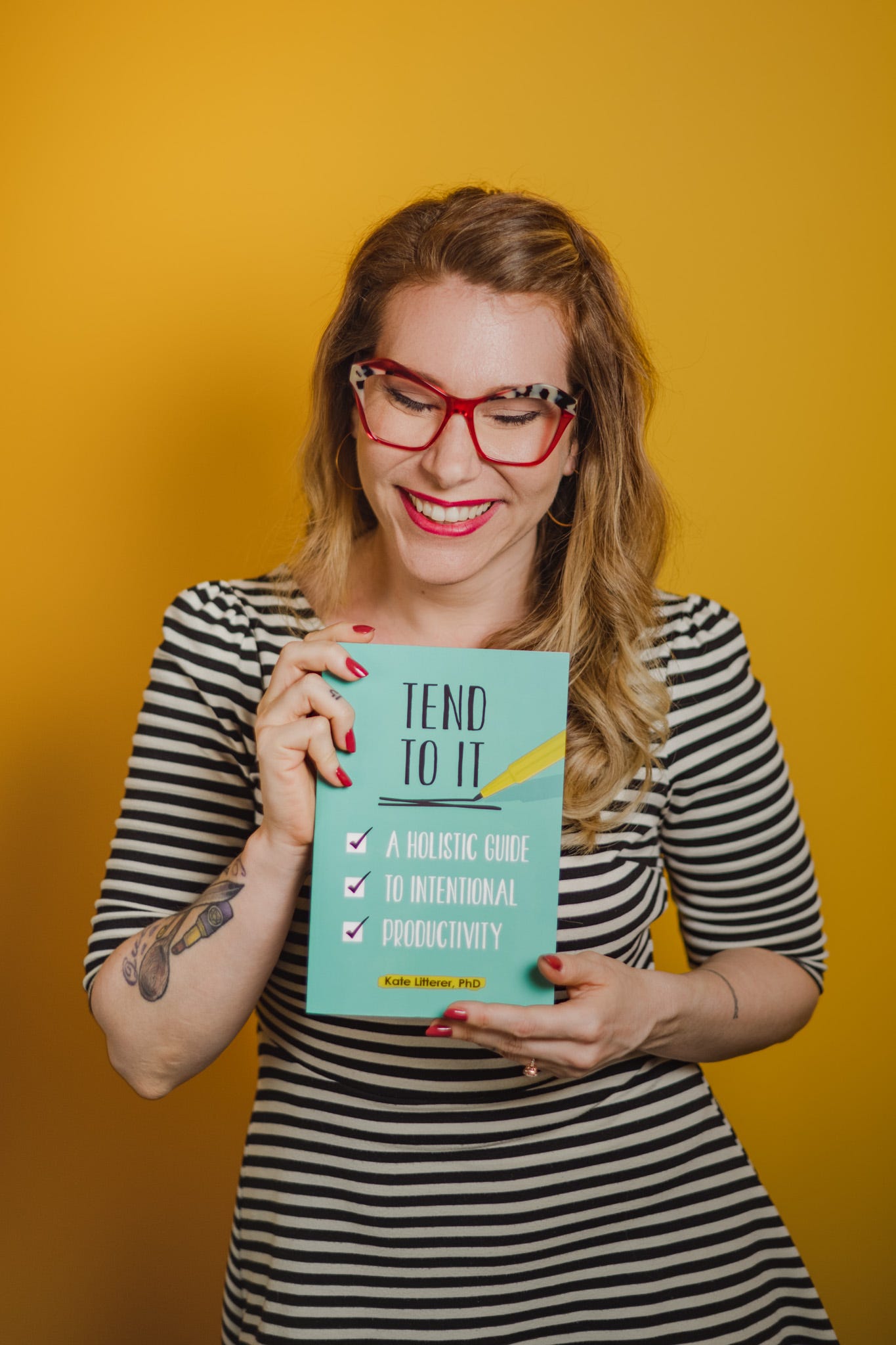 Kate holding her book Tend to It: A Holistic Guide to Intentional Productivity.