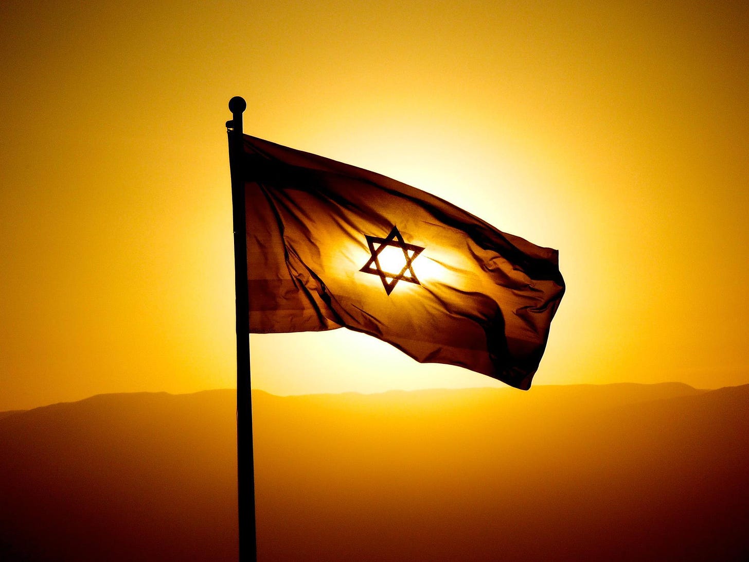 the sun rising behind an Israeli flag