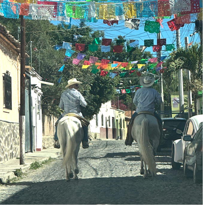 People riding horses through a street