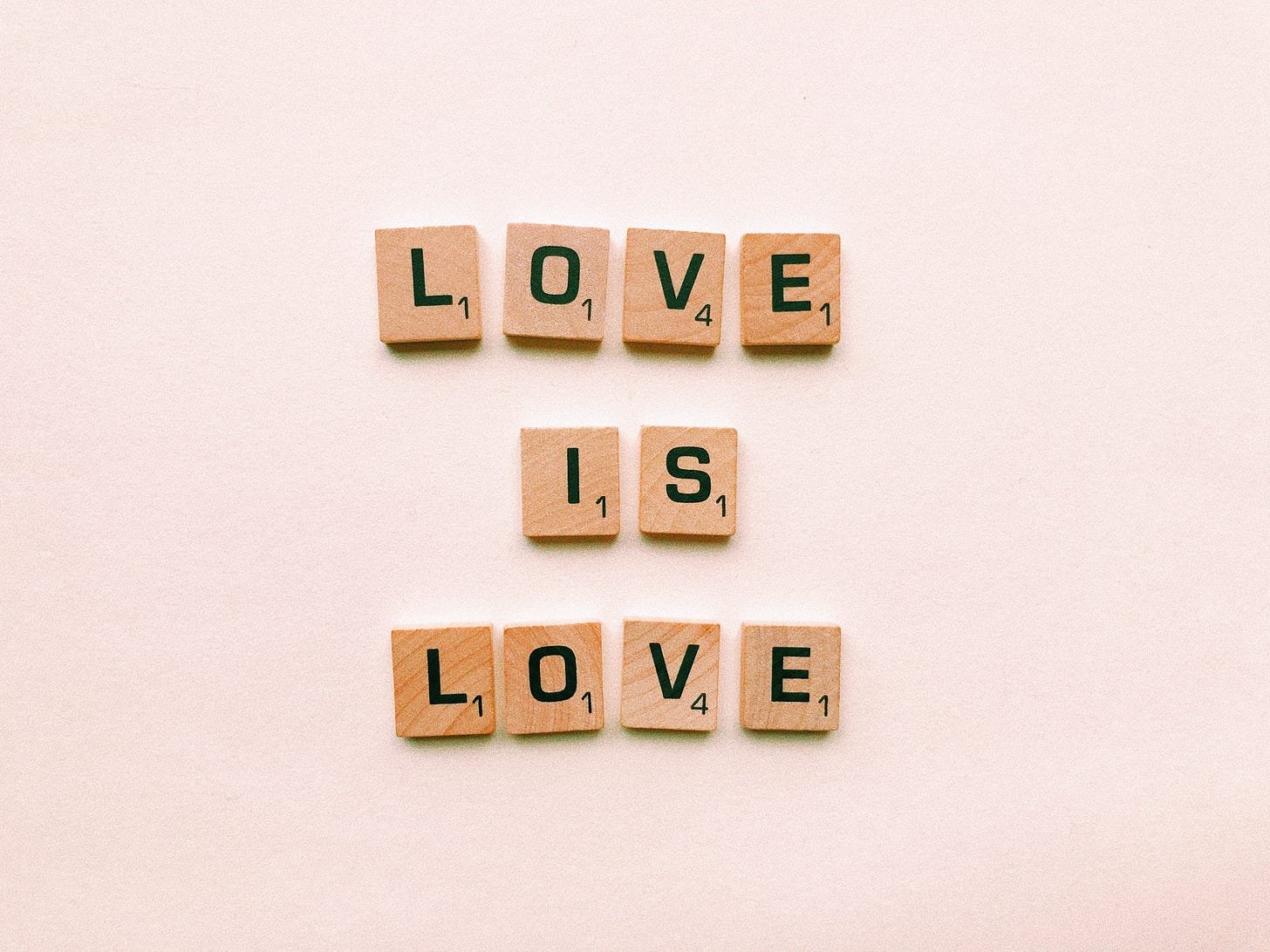 Scrabble tiles on a bege background spell love is love