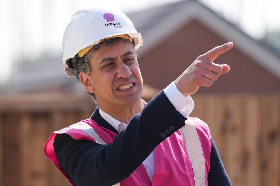 Ed Miliband, the UK's new Secretary of State for Energy Security and Net Zero, points while wearing an Octopus Energy hard hat.