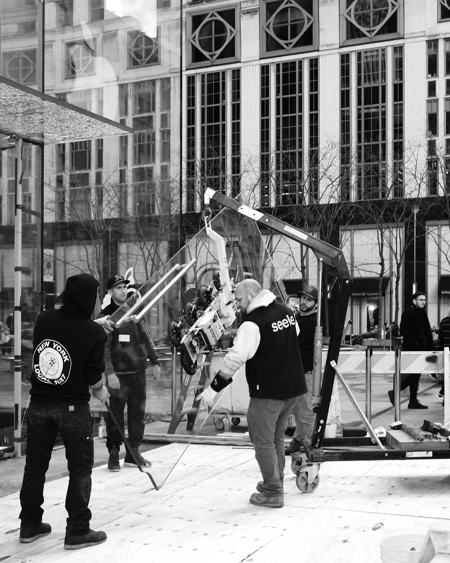A crew guides a glass door into place at Apple Fifth Avenue.