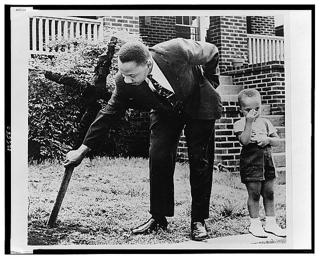 Martin Luther King, Jr., pulls up cross that was burned on lawn of his  home, as his son stands next to him, Atlanta, Georgia] | Library of Congress