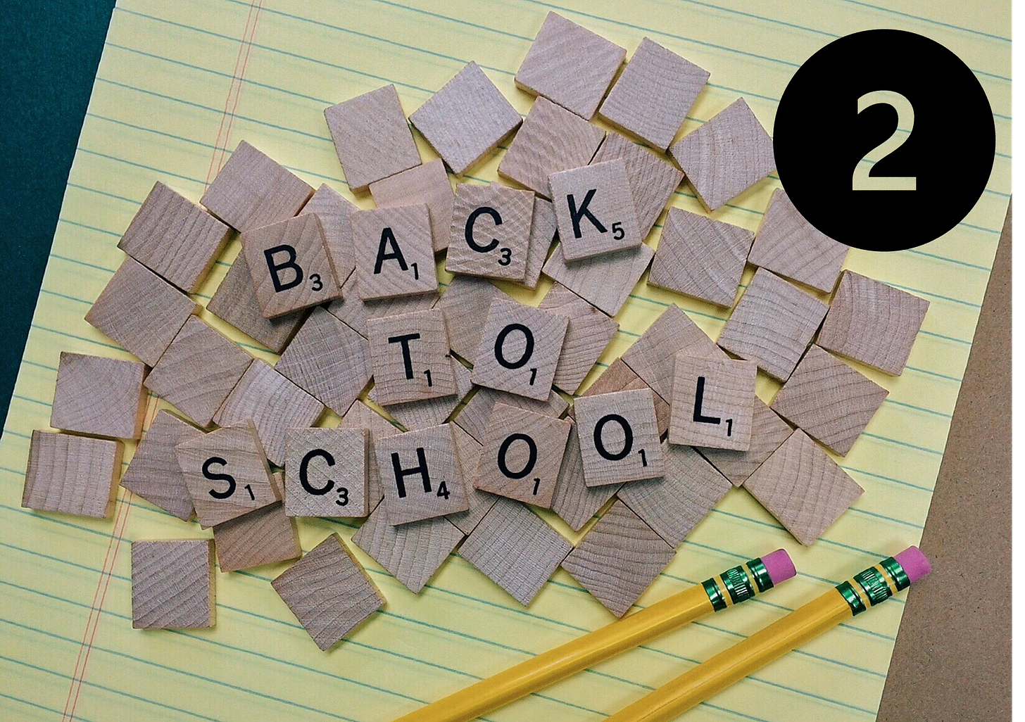 yellow notepad with scrabble letters spelling out back to school on top with a large number two in the top right corner