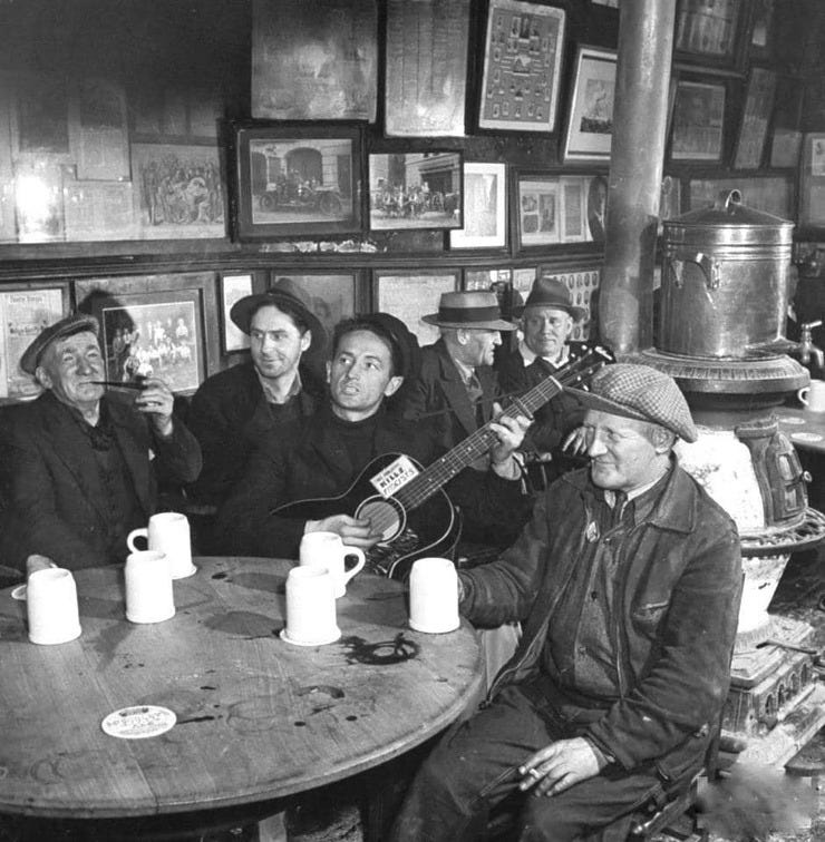 Woody Guthrie strumming his guitar in 1943 at McSorley's (NYC)