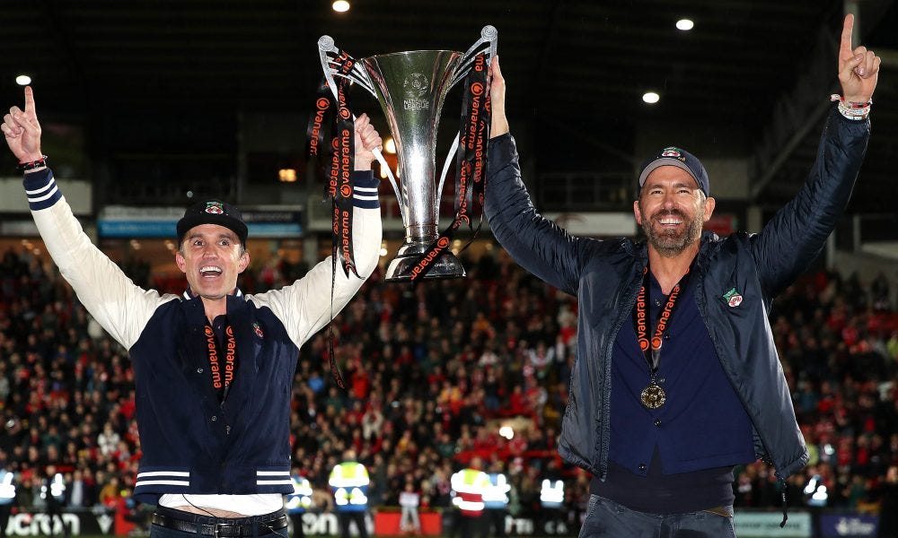 Ryan Reynolds and Rob McElhenney holding trophy after Wrexham was promoted to League Two