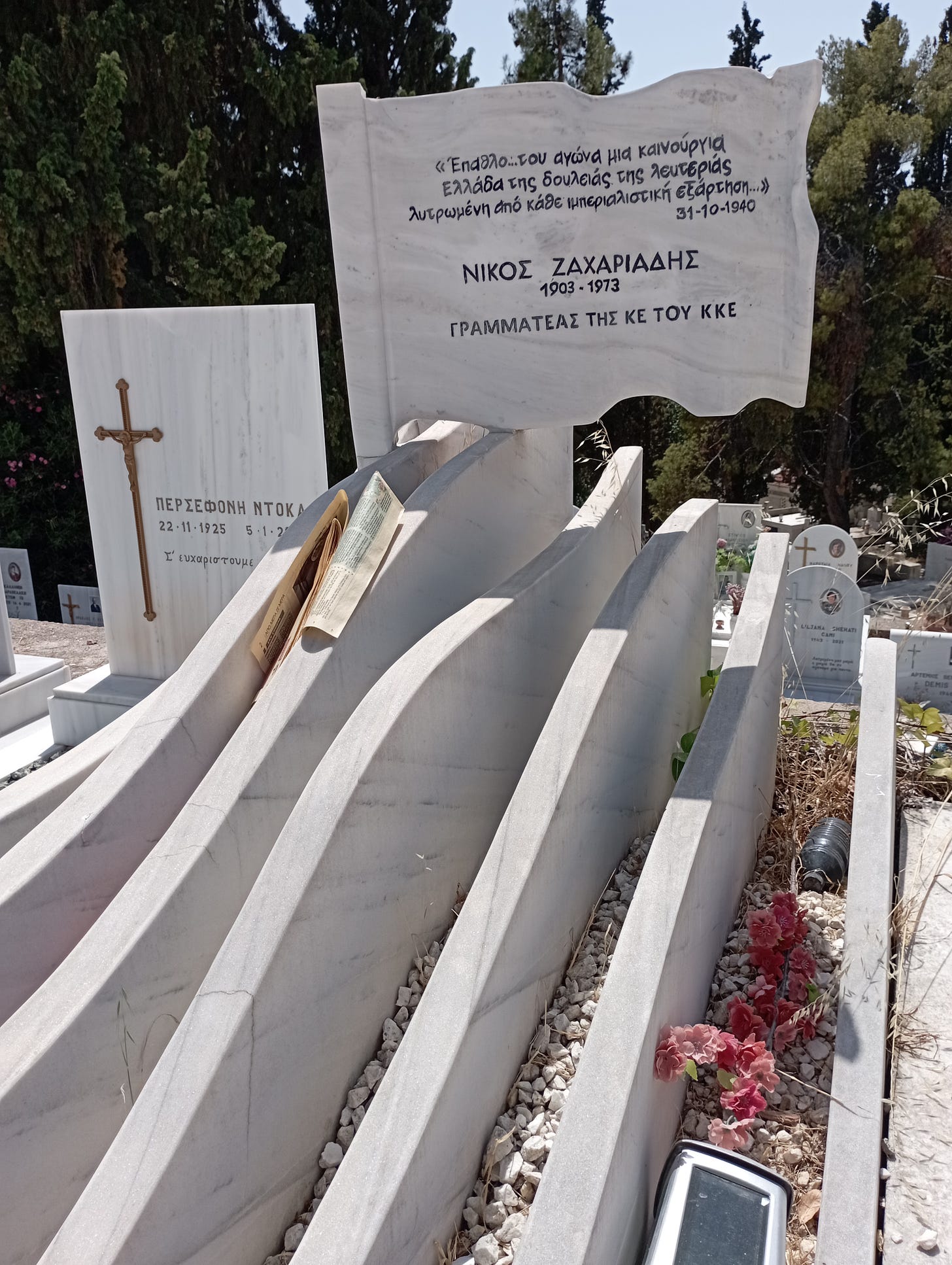 la tomba di nikos zachariadis con lapide a forma di bandiera e onde di marmo bianco