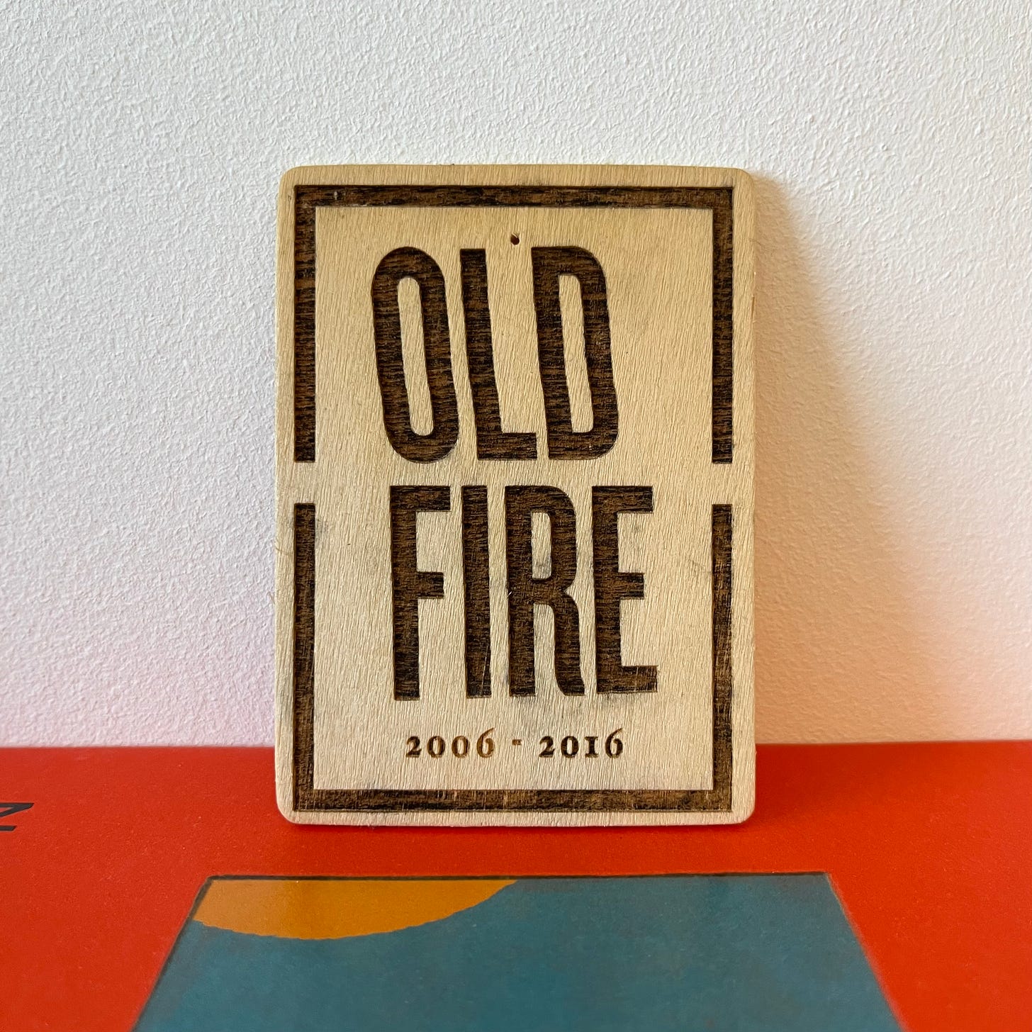 A wooden emblem, with the words Old Fire 2006-2016 engraved into it, on top of a copy of Klara and the Sun