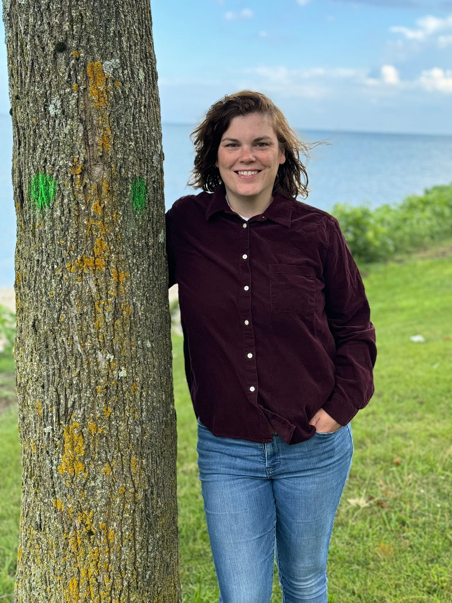 author photo of Jen St. Jude, next to a tree, with the lake behind them