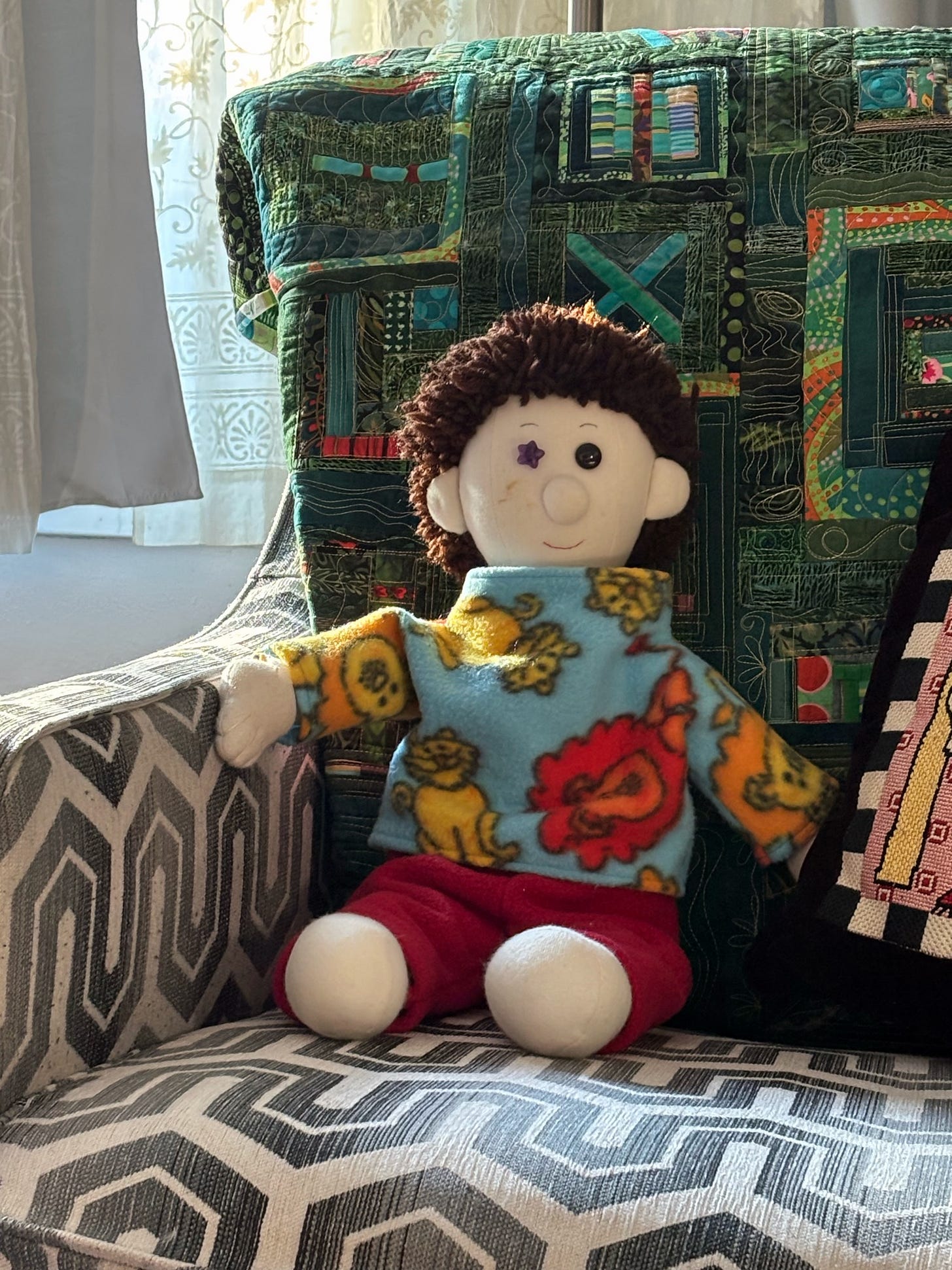 A handmade boy doll sitting in a chair