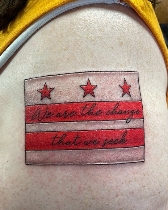 My left arm with a new tattoo of the DC state flag, with “we are the change that we seek” written in script on the red bars