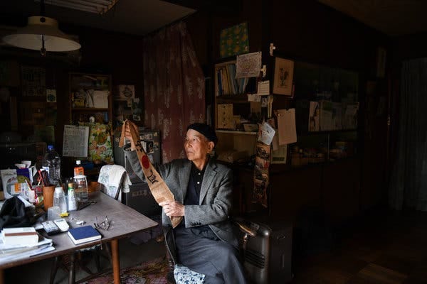 Katsumoto Saotome at his home in Tokyo with his hachimaki headband from World War II. He worked at a factory to support the war when he was 12. He and other students sometimes wore the headbands on their way to work.