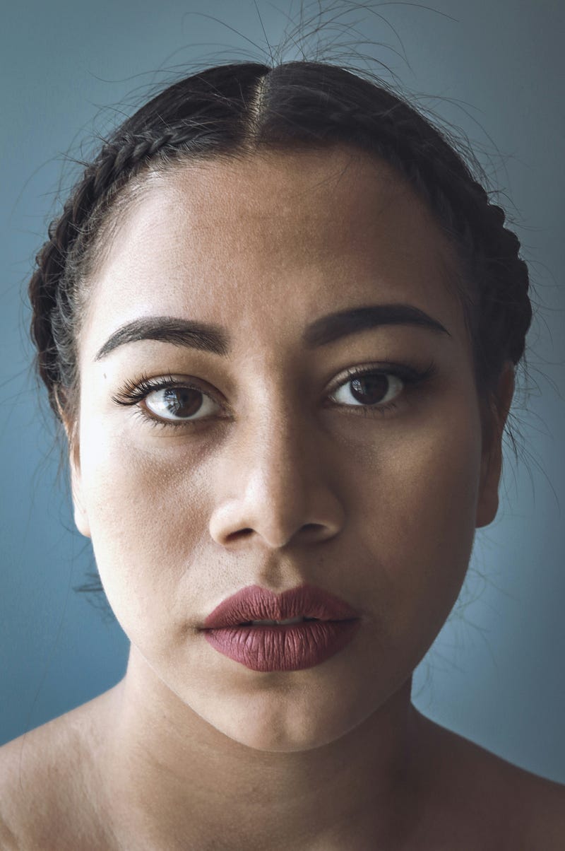 Woman looking at camera with dark eyes and expressive face.