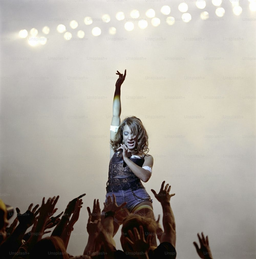 a woman standing on top of a stage with her arms in the air