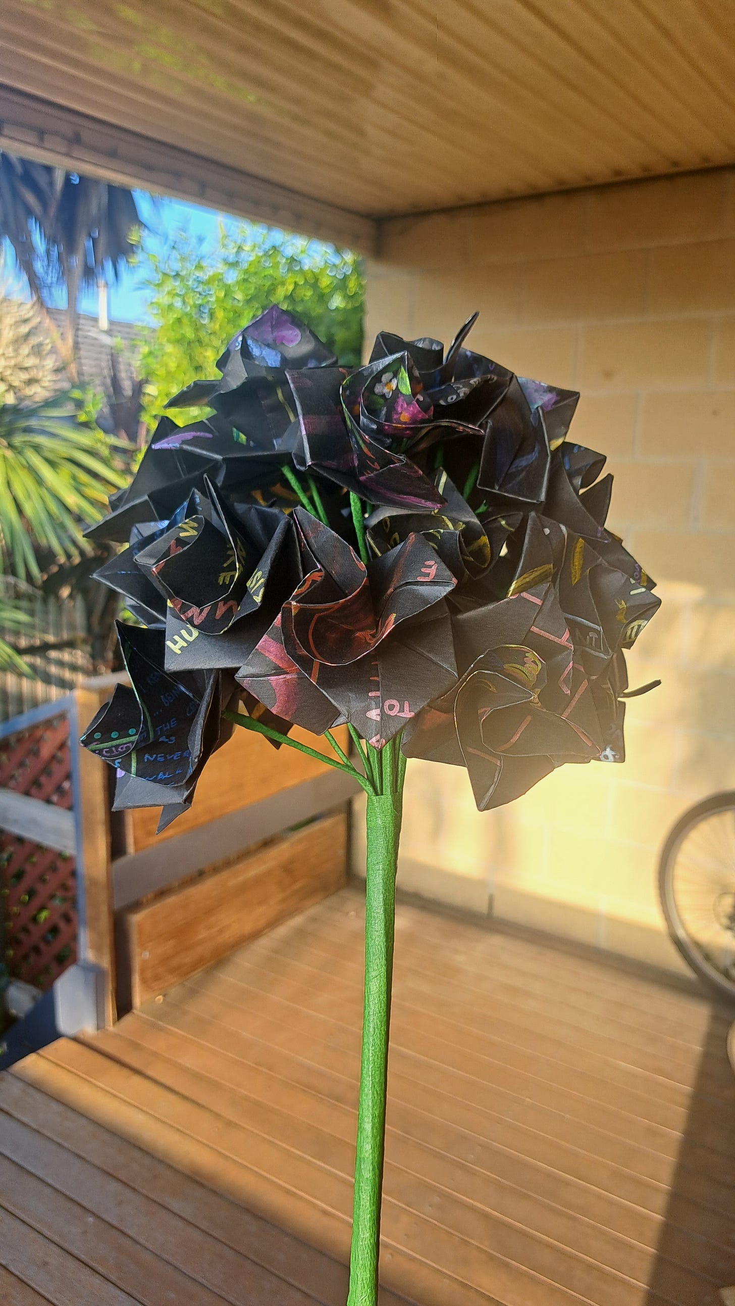 A boquet of black paper flowers with metalic designs and writing on them.