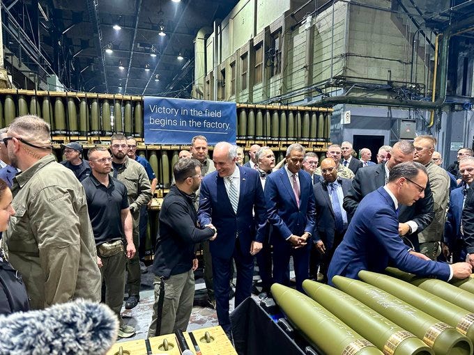 A picture of Senator Casey shaking President Zelenskyy’s hand surrounded by several other people and ammunition casings.