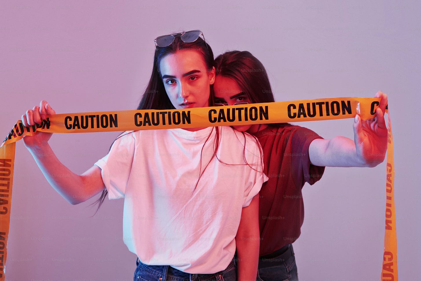 White and red shirts. Studio shot indoors with neon light. Photo of two beautiful twins.