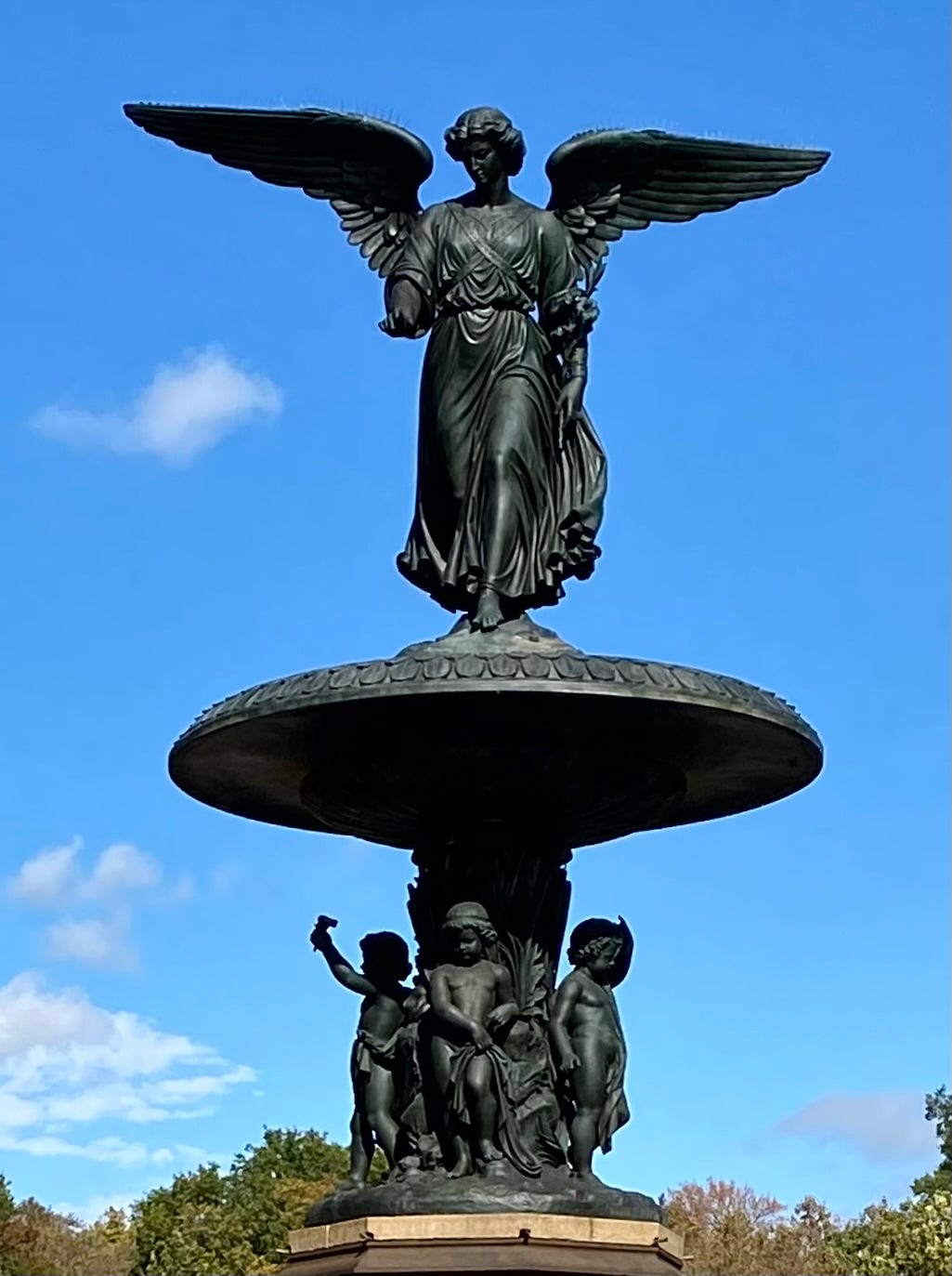 The angel of the Bethesda fountain in the sunshine against a blue sky.