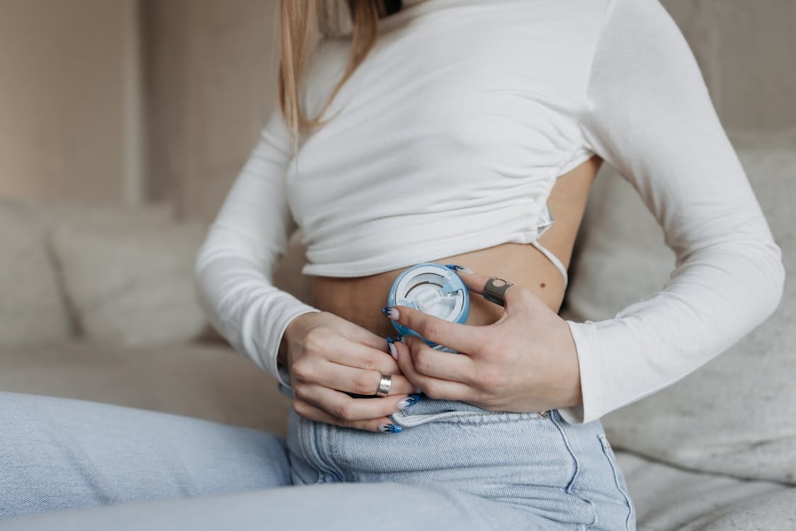 Free Close-up of a woman using an insulin pump, highlighting diabetes management. Stock Photo